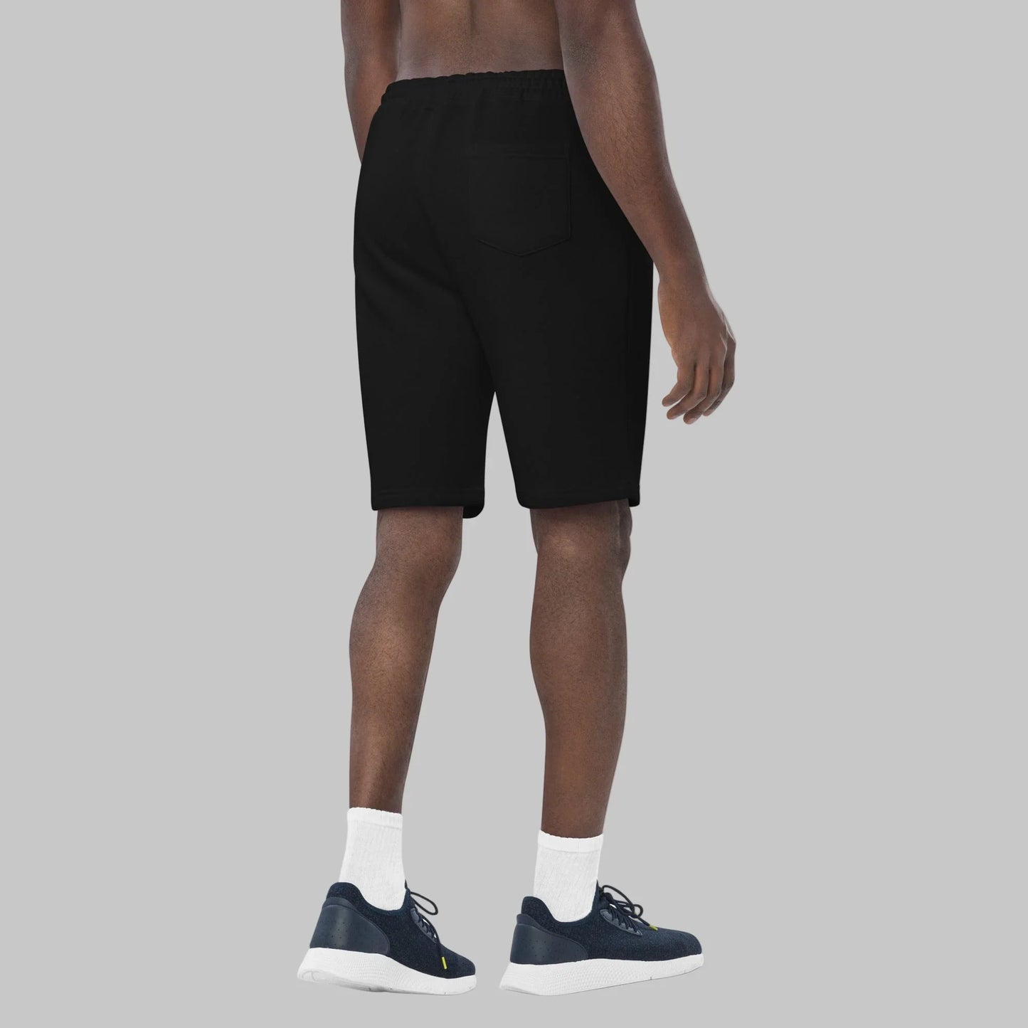 Person wearing black fleece shorts on a grey background
