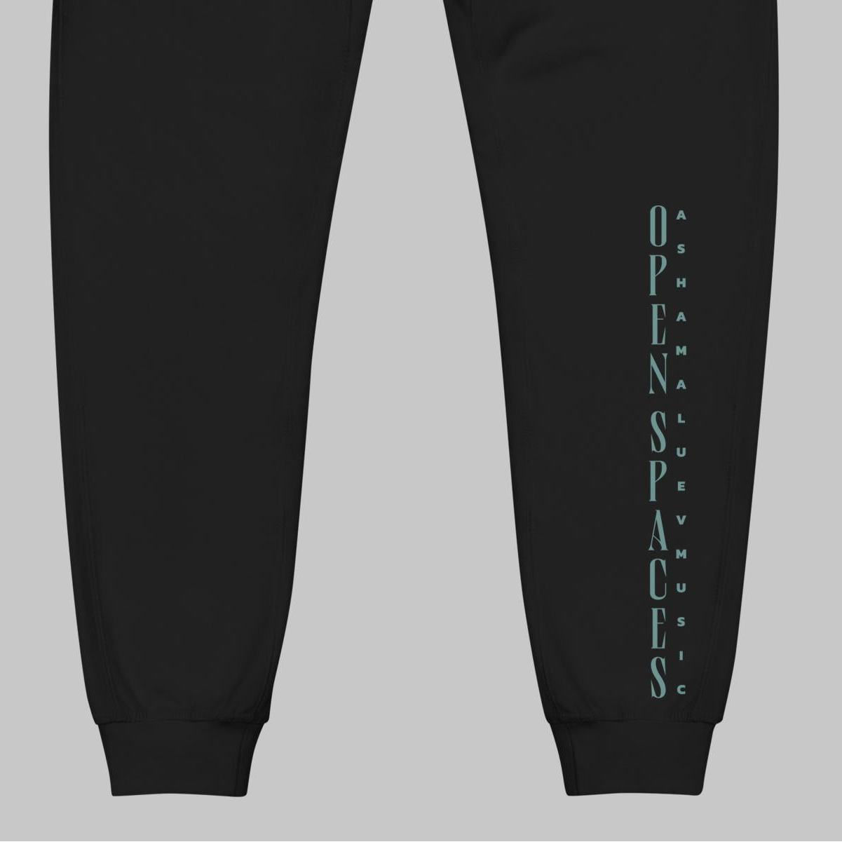 Black fleece sweatpants with turquoise text 'Open Spaces' and 'AShamaluevMusic' on a gray background