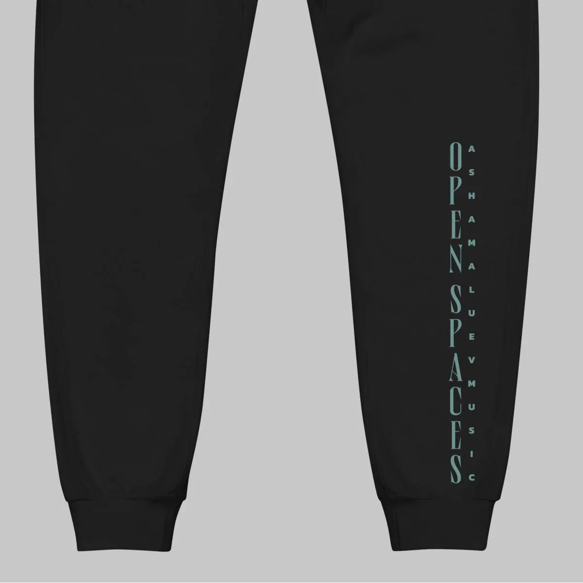 Black fleece sweatpants with turquoise text 'Open Spaces' and 'AShamaluevMusic' on a gray background