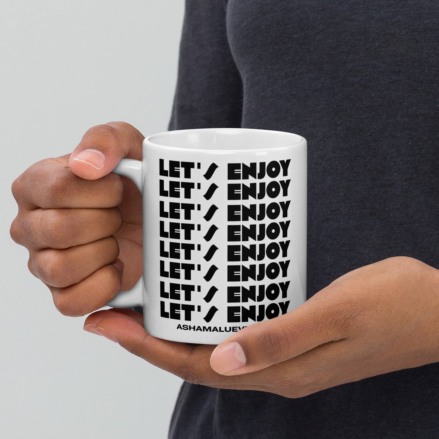 Person holding a white mug with 'LET'S ENJOY' text in black.