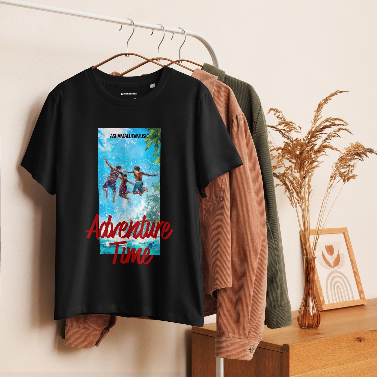 Black women's short sleeve t-shirt with 'Adventure Time' graphic and text 'AShamaluevMusic' on a hanger against a neutral background