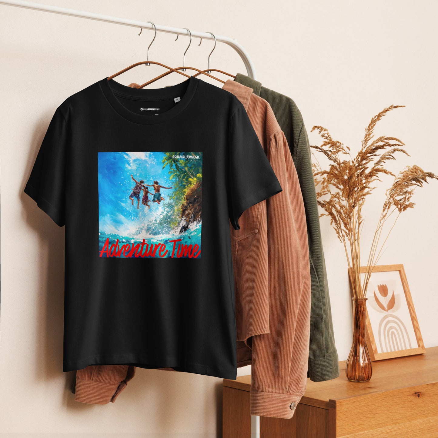 Black women's short sleeve t-shirt with 'Adventure Time' graphic and 'AShamaluevMusic' text on a hanger against a neutral background