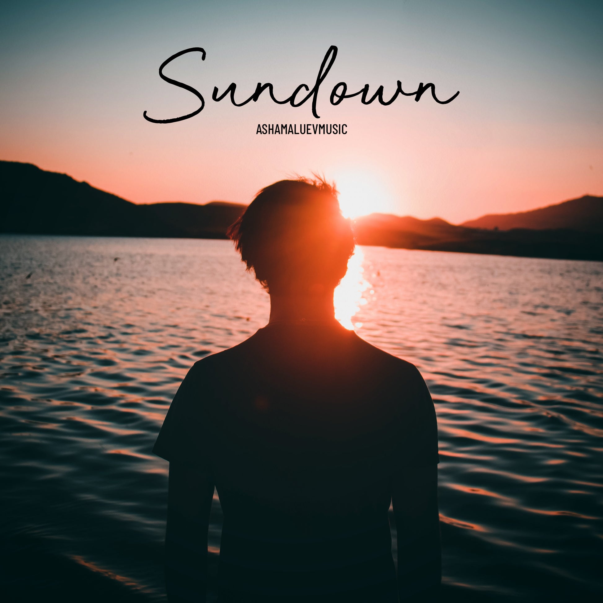 Cover art of the music track 'Sundown' by AShamaluevMusic, which shows the person standing by a lake with sunset.