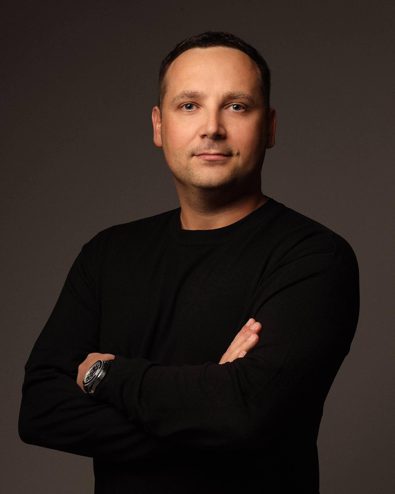 Aleksandr Shamaluev, aka AShamaluevMusic wearing a black sweater with arms crossed against a dark background