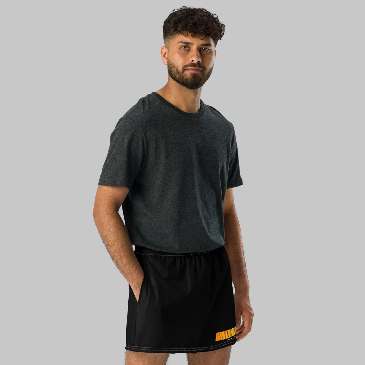 Man wearing black athletic shorts with print 'Amazing World' and 'AShamaluevMusic' logo a gray background