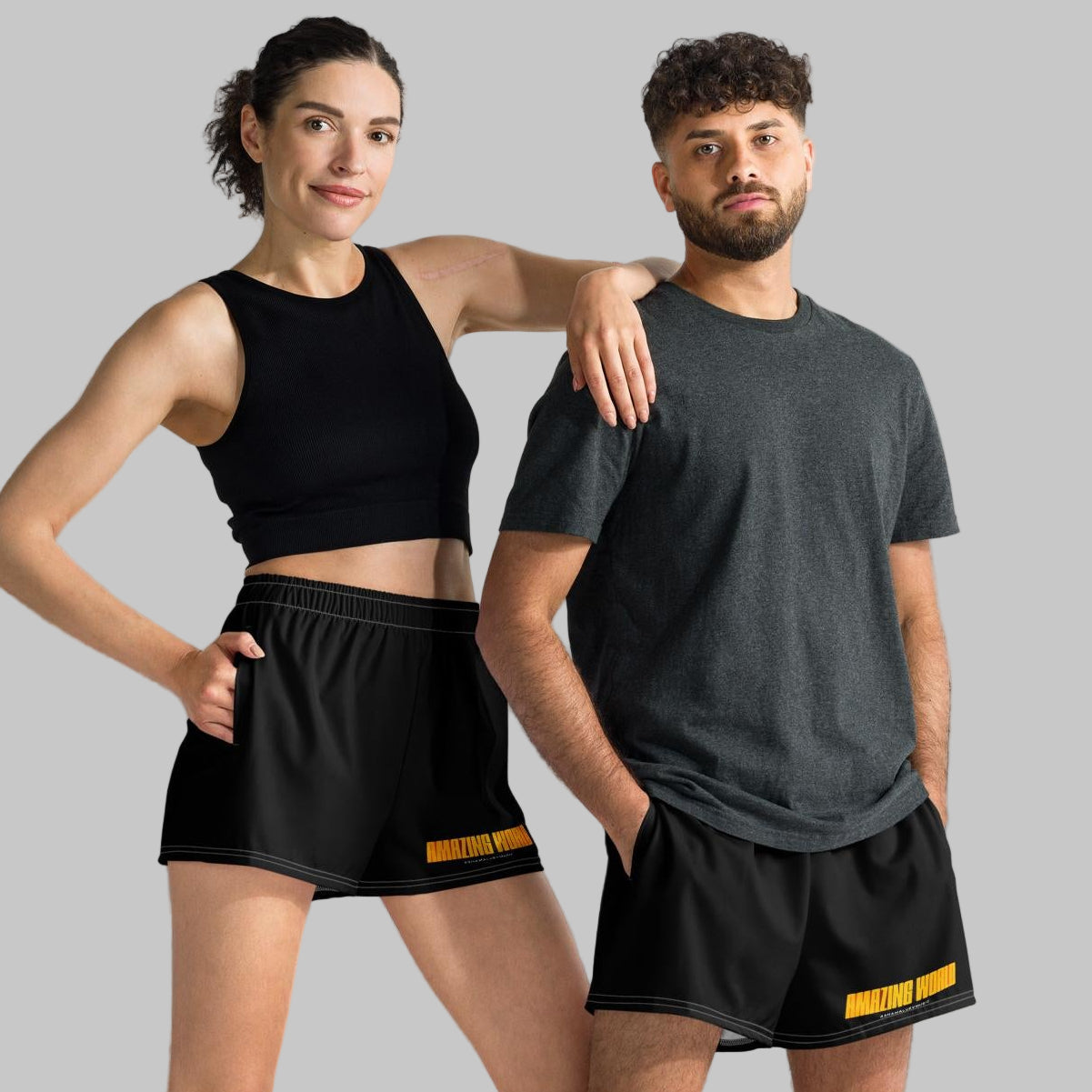 Two people wearing black athletic shorts with print 'Amazing World' and 'AShamaluevMusic' logo a gray background