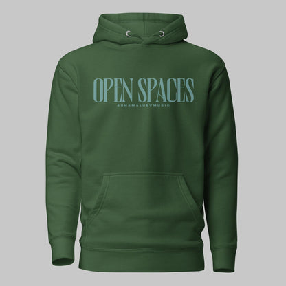 Forest green unisex premium hoodie with turquoise text 'Open Spaces' and 'AShamaluevMusic' on a gray background