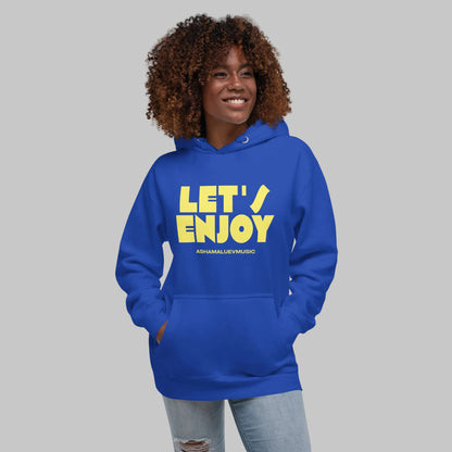 Woman wearing a blue unisex pullover hoodie with yellow text 'Let's Enjoy' and 'AShamaluevMusic' on a gray background.
