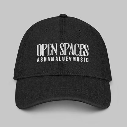 Black denim cap with white text 'Open Spaces' and 'AShamaluevMusic' on a gray background