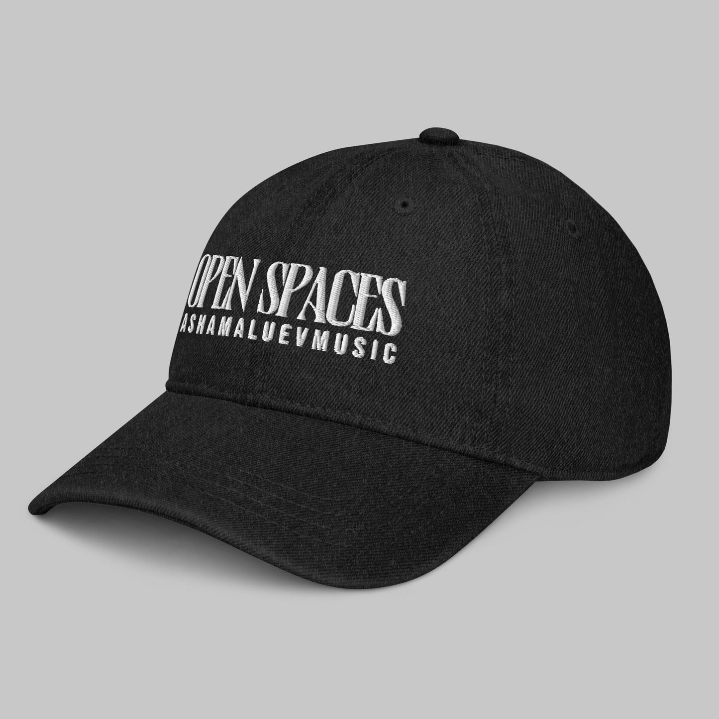 Black denim cap with white text 'Open Spaces' and 'AShamaluevMusic' on a gray background