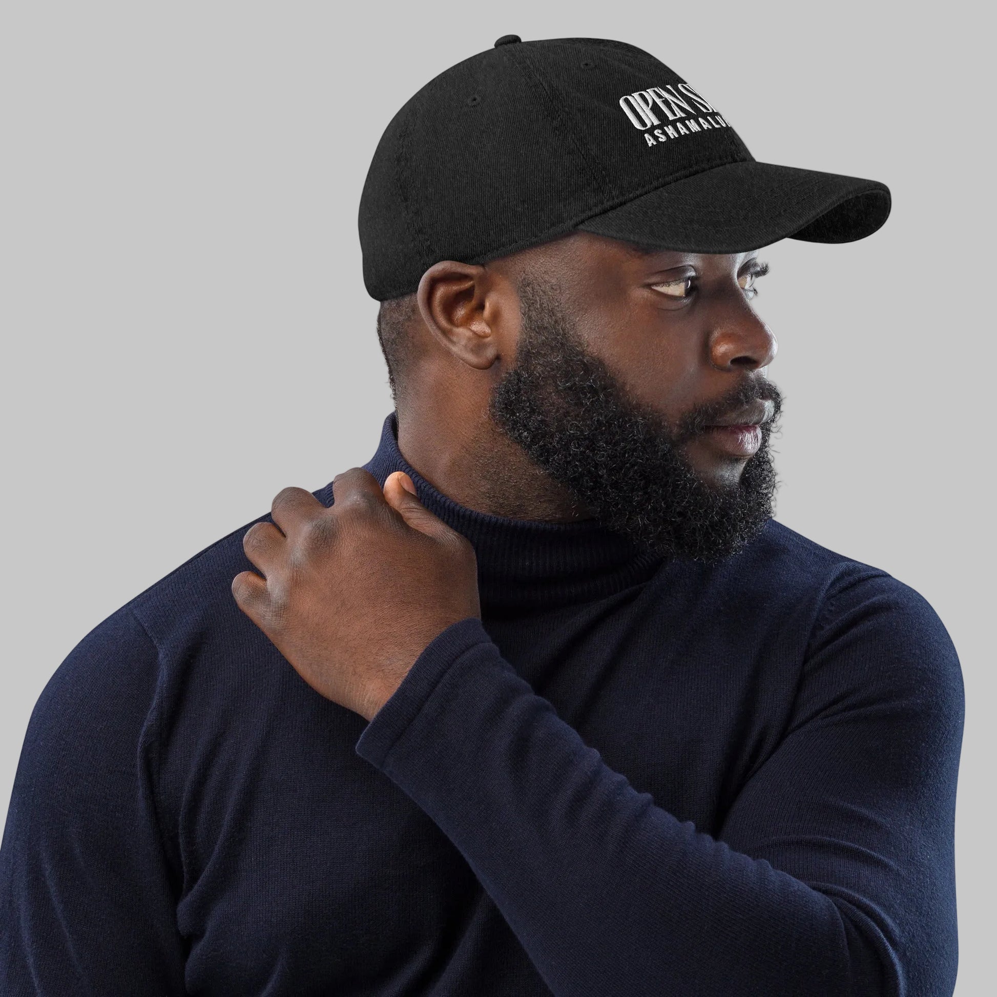 Man wearing a black denim cap with text 'Open Spaces' and 'AShamaluevMusic' on a gray background.