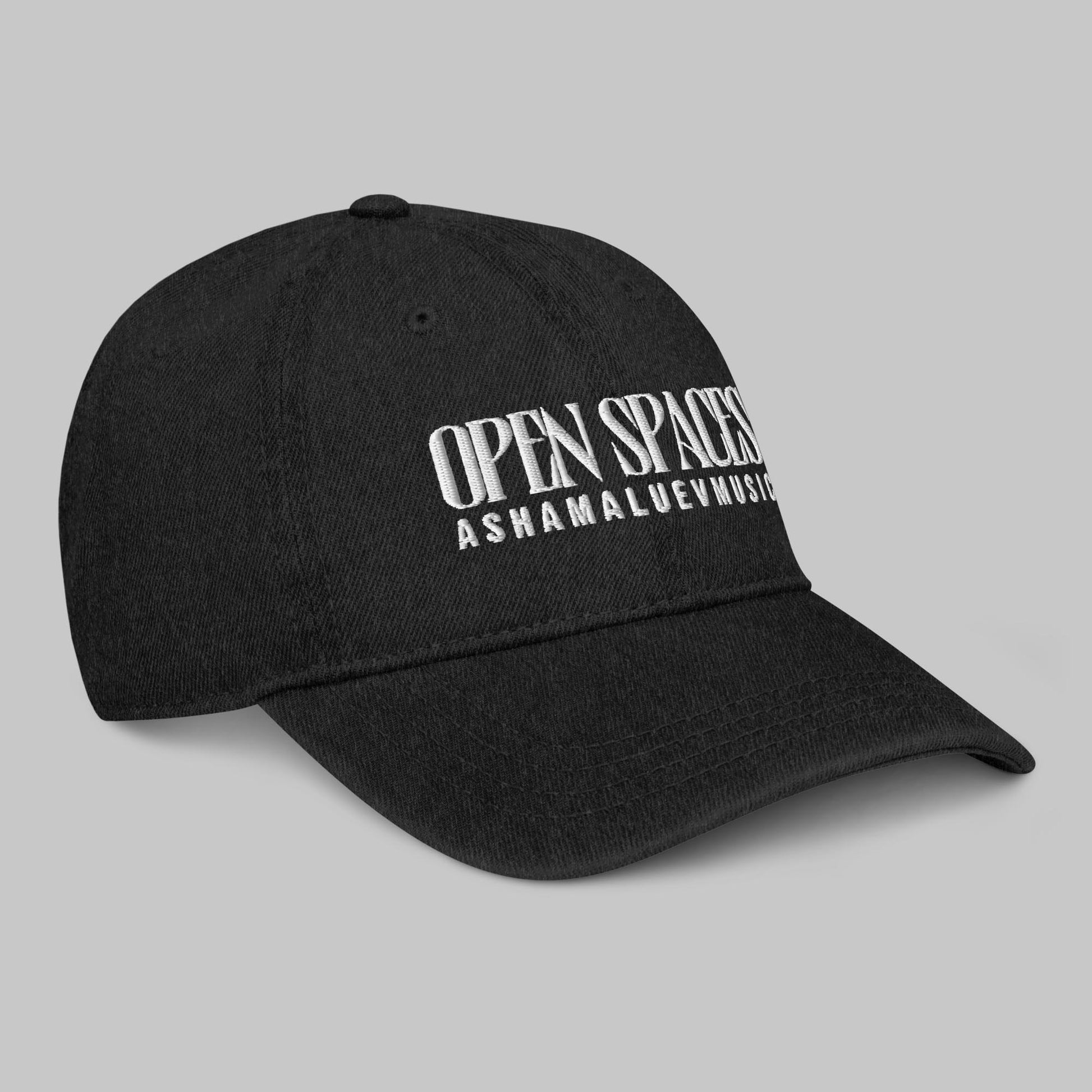 Black denim cap with white text 'Open Spaces' and 'AShamaluevMusic' on a gray background