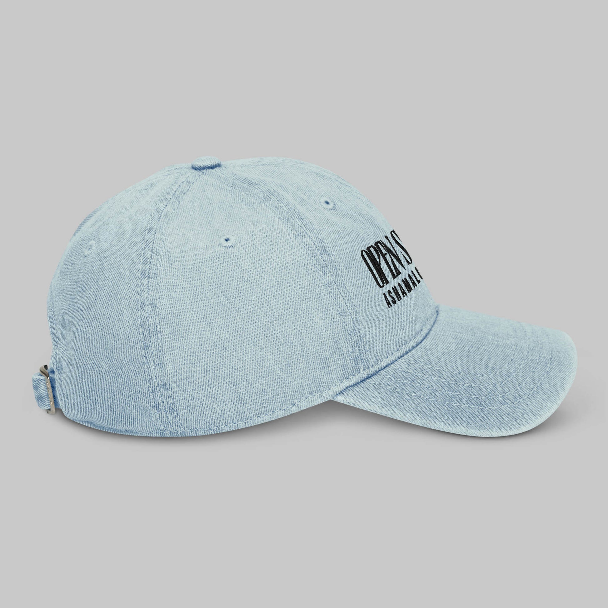 Light blue denim cap with black text 'Open Spaces' and 'AShamaluevMusic' on a gray background