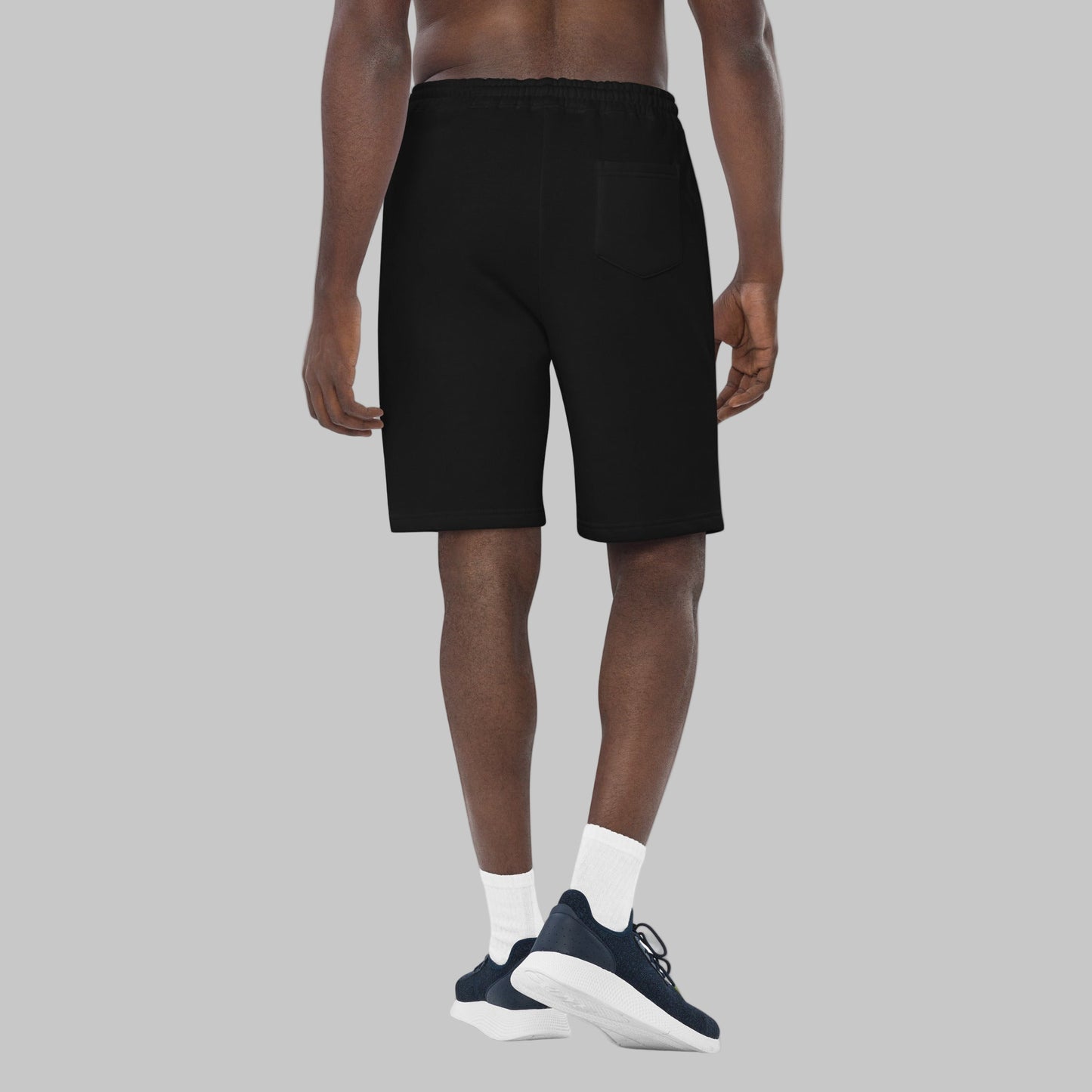 Man wearing black fleece shorts with embroidery 'MEGAPOLIS' and 'AShamaluevMusic' logo on the left leg and a drawstring waistband.