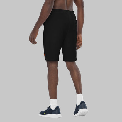 Man wearing black fleece shorts with embroidery 'MEGAPOLIS' and 'AShamaluevMusic' logo on the left leg and a drawstring waistband.