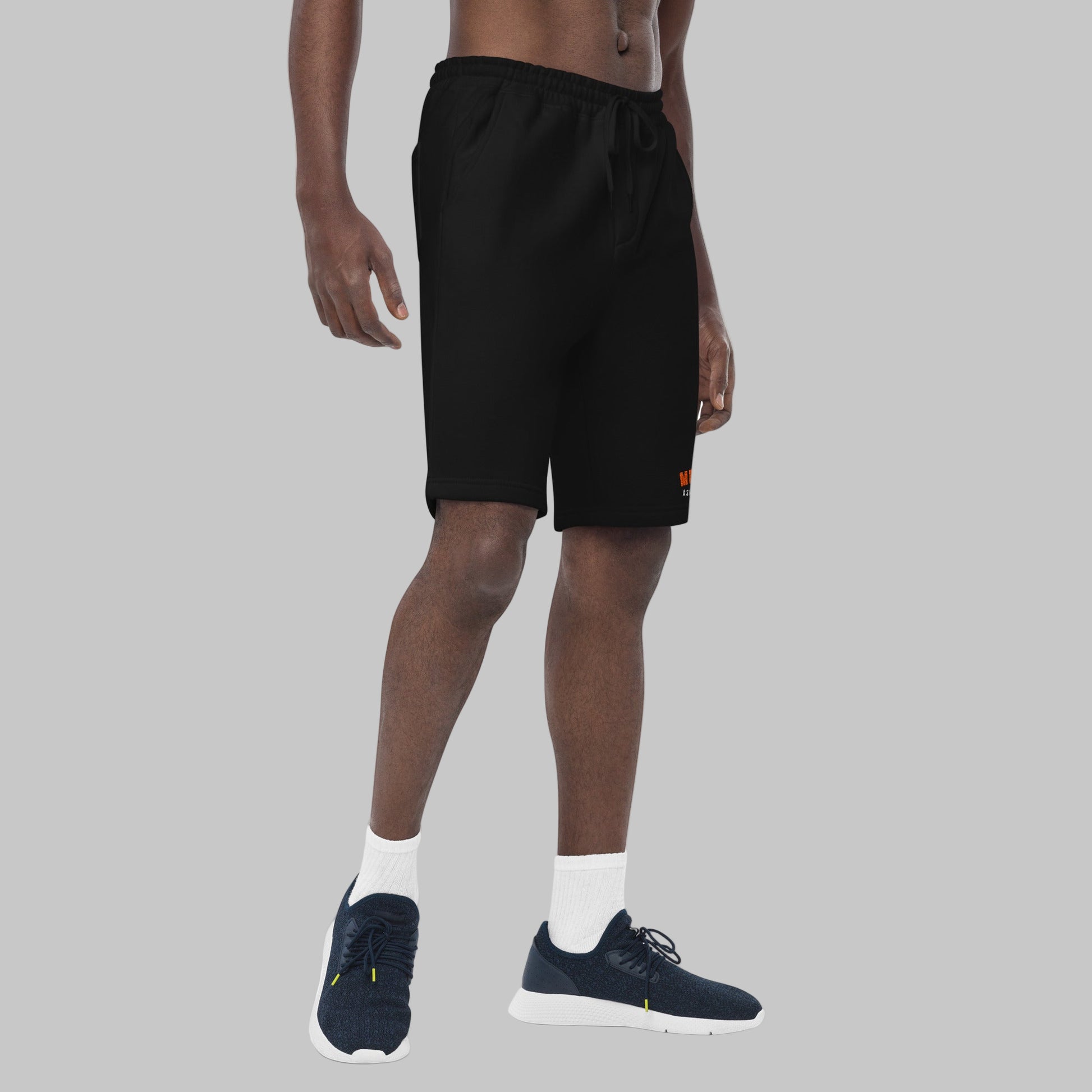 Man wearing black fleece shorts with embroidery 'MEGAPOLIS' and 'AShamaluevMusic' logo on the left leg and a drawstring waistband.