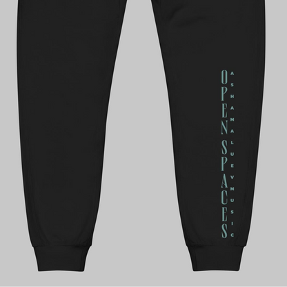 Black fleece sweatpants with turquoise text 'Open Spaces' and 'AShamaluevMusic' on a gray background