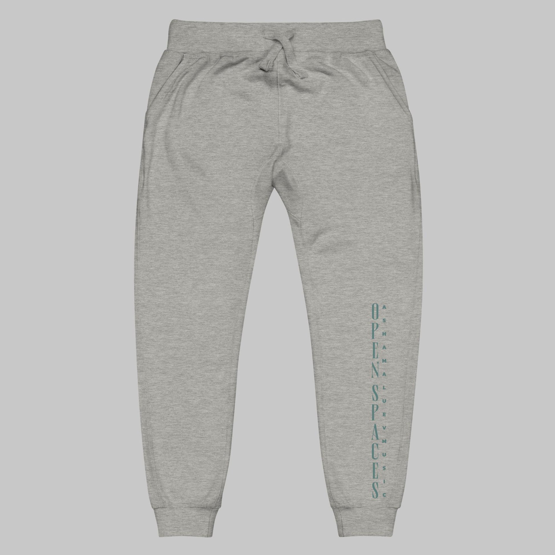 Carbon grey unisex fleece sweatpants with turquoise text 'Open Spaces' and 'AShamaluevMusic' on a gray background.