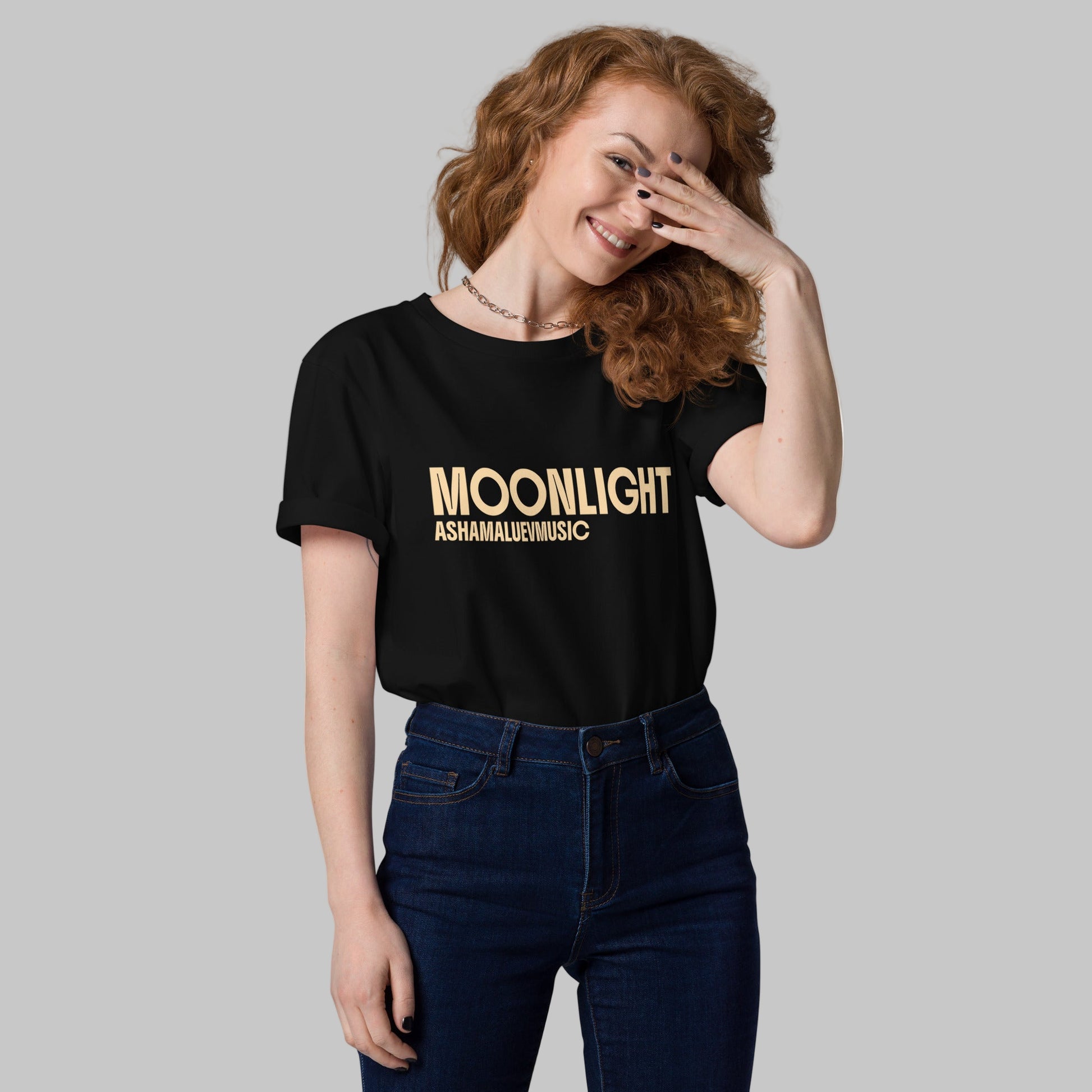 Woman wearing a black organic cotton t-shirt with 'Moonlight' print and AShamaluevMusic logo on a light grey background