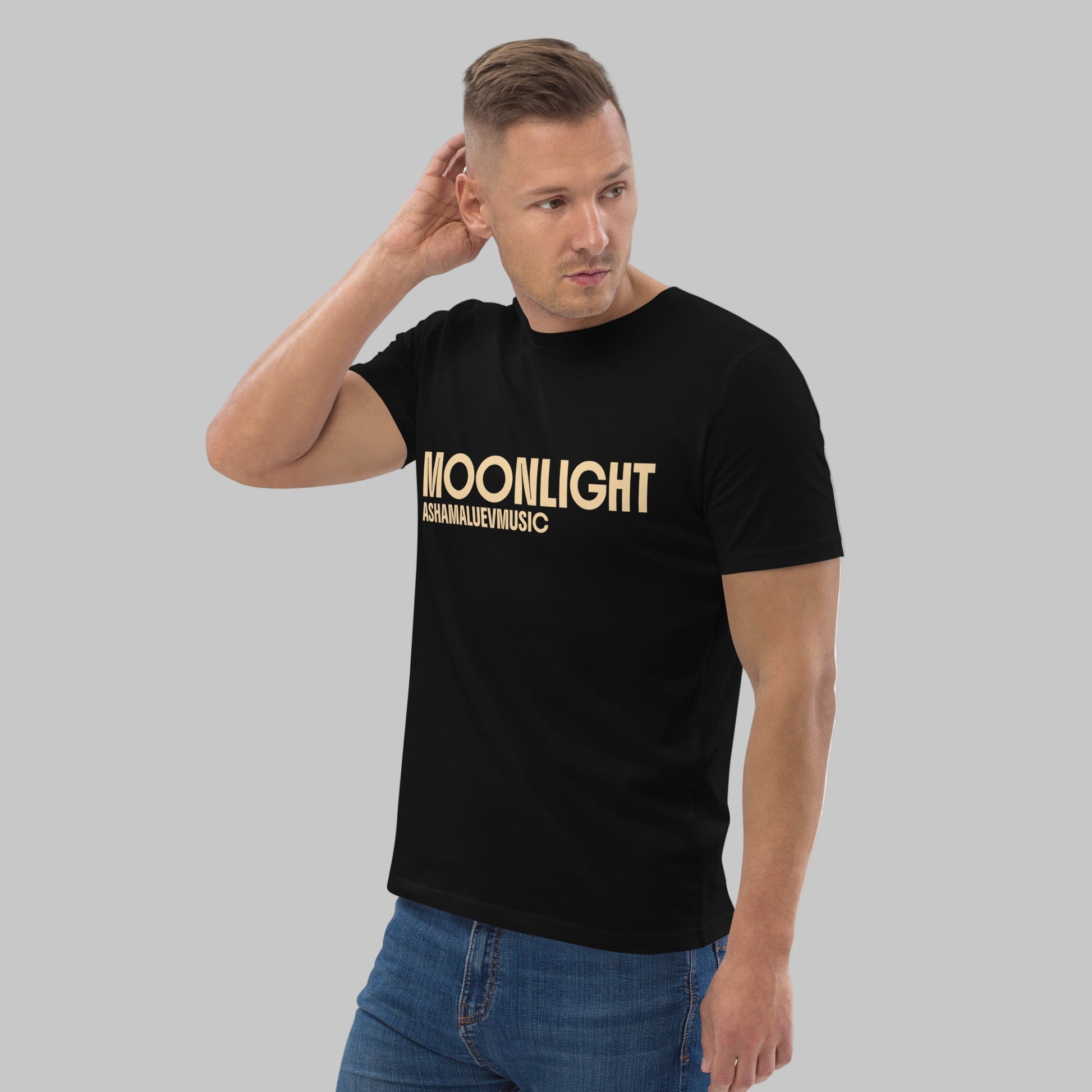 Man wearing a black organic cotton t-shirt with 'Moonlight' print and AShamaluevMusic logo on a light grey background