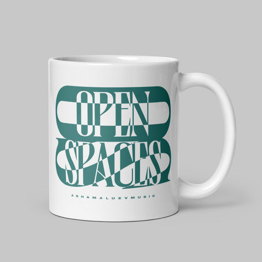 White mug (11 oz) with teal text 'Open Spaces' by AShamaluevMusic on a gray background