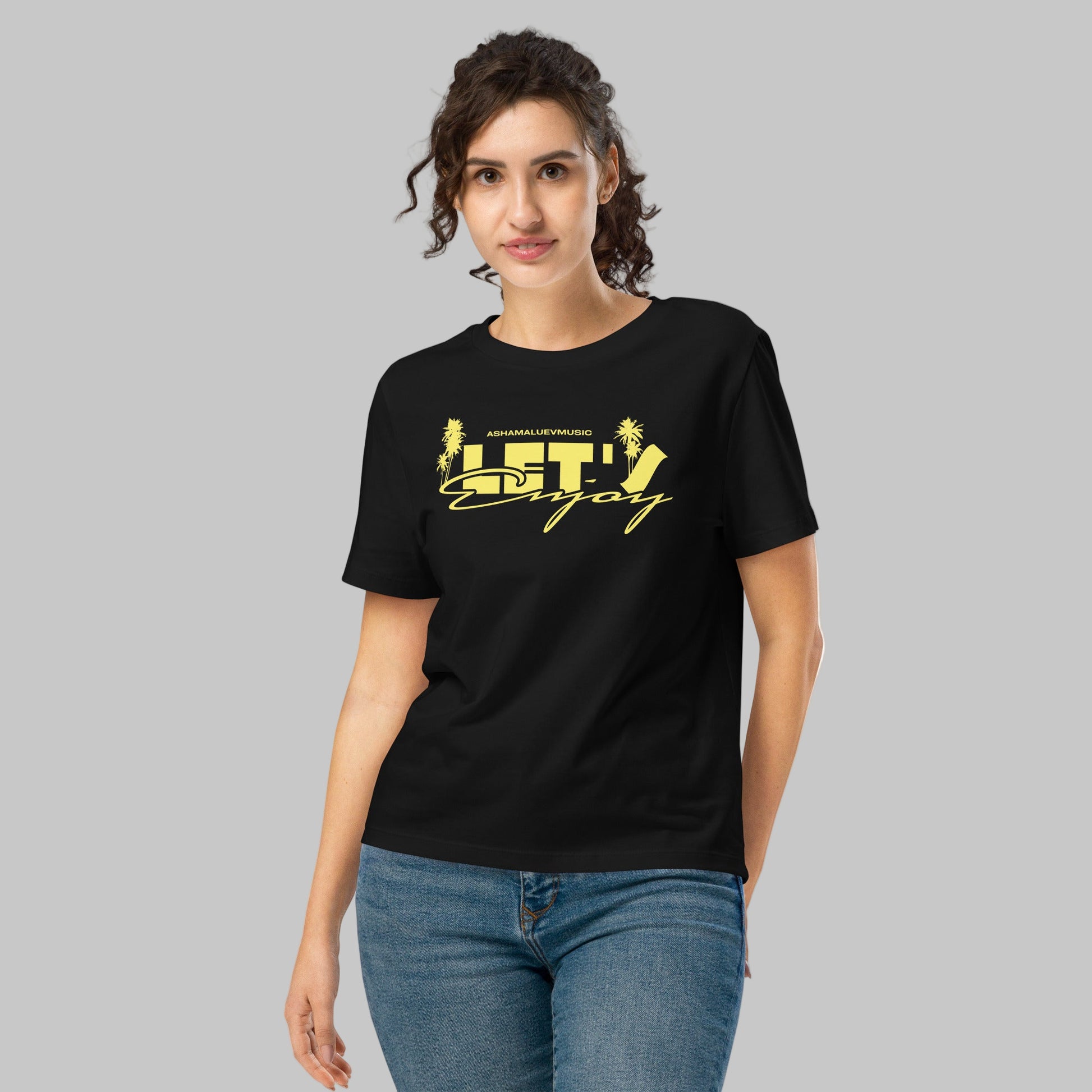 Woman wearing a black t-shirt with yellow graphics 'Let's Enjoy' and AShamaluevMusic logo on a grey background