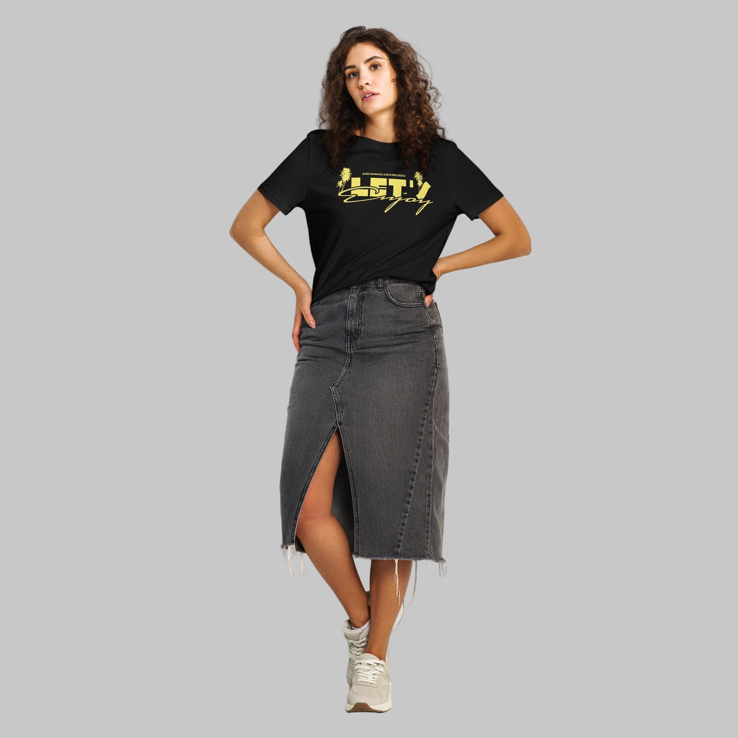 Woman wearing a black t-shirt with yellow graphics 'Let's Enjoy' and AShamaluevMusic logo on a grey background