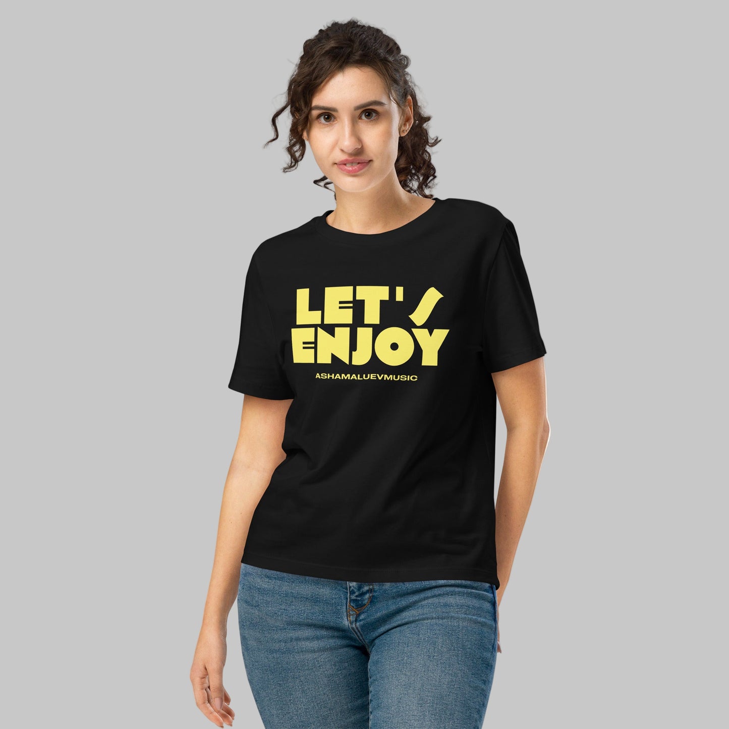 Woman wearing a black t-shirt with a 'Let's Enjoy' print and AShamaluevMusic logo on a grey background
