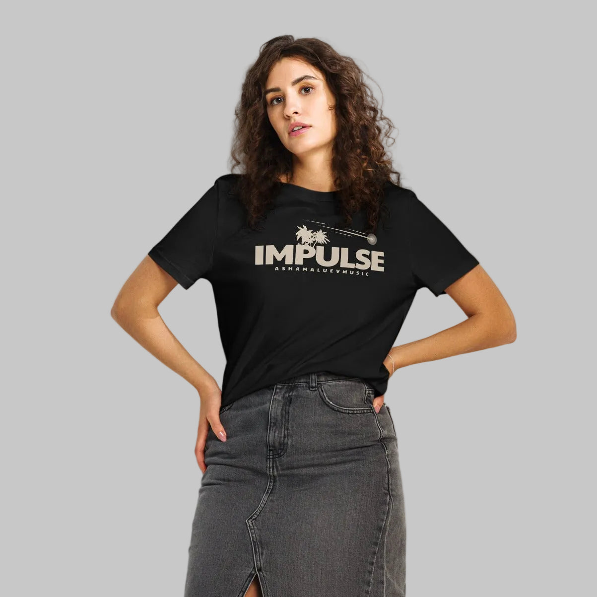 Woman wearing a black organic short sleeve t-shirt with beige text 'IMPULSE' and 'AShamaluevMusic' on a gray background